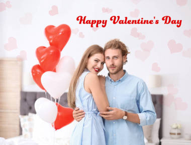 在卧室里拿着气球的年轻夫妇, 并发短信祝情人节快乐