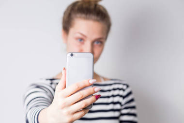 特寫鏡頭的女性手拿著智能手機(jī)采取自拍, 前景在焦點(diǎn)