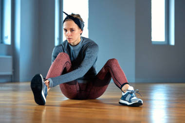 美麗的年輕女子運(yùn)動員系鞋帶運(yùn)動鞋, 同時放松從力量訓(xùn)練在健身房。健身和運(yùn)動