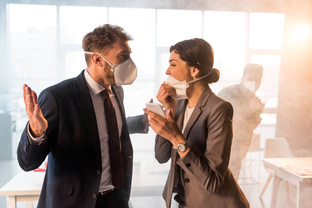 带着面具的惊恐万状的女人在办公室里拿着烟看着受惊的同事的选择性焦点 带着面具的惊恐万状的女人在办公室里拿着烟看着受惊的同事的选择性焦点