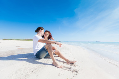 年輕夫婦坐在加勒比海灘