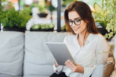 年轻的女商人在咖啡馆的夏季露台上看平板电脑