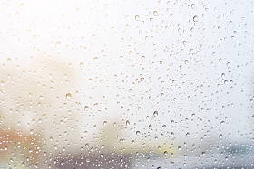 在背景模糊的多云天气下, 玻璃上的雨滴