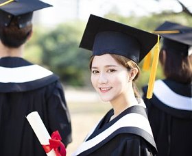 微笑的年轻女子在毕业时显示她的文凭