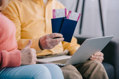 裁剪视图的高级夫妇显示拇指上的标志和持有机票与护照