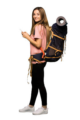 全身年轻背包客妇女发送消息与手机在孤立的背景