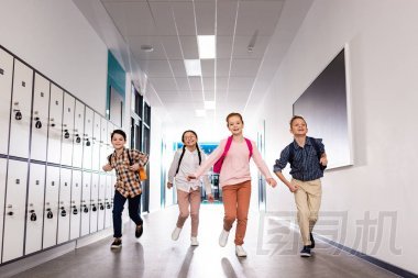 四個興奮的學(xué)生, 放學(xué)后背著背包在走廊上跑