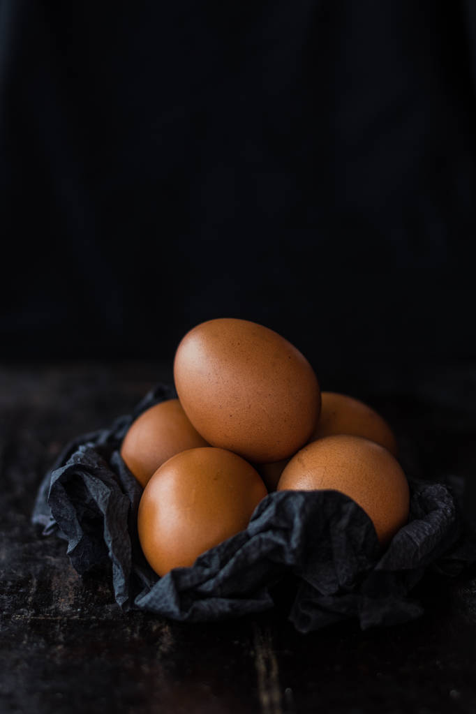 黑色餐巾纸上的棕色鸡蛋在黑暗的背景 黑色餐巾纸上的棕色鸡蛋在黑暗的背景