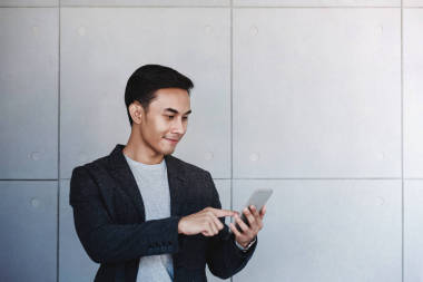 年輕的快樂商人的肖像使用智能手機。站立 b