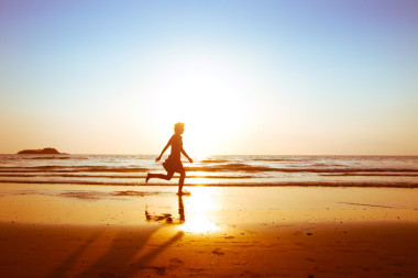 女孩在日落時(shí)在沙灘上跑