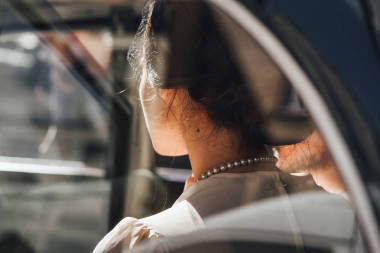 年轻新娘的后视图与优雅的项链坐在汽车