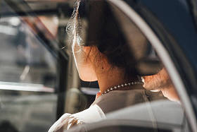 年轻新娘的后视图与优雅的项链坐在汽车