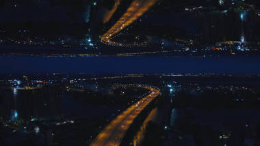 空中夜景的河橋與移動的汽車和城市與夜燈, 鏡子地平線的效果。媒體。令人驚嘆的夜景城市和跨江大橋, 開始主題