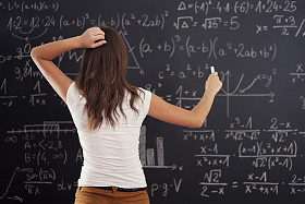 年轻女子看黑板上的数学问题照片