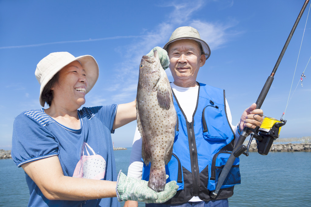 亚洲高级夫妇捕鱼和显示大石斑