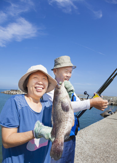 高級(jí)對(duì)快樂(lè)的夫妻捕魚(yú)和顯示大石斑魚(yú)