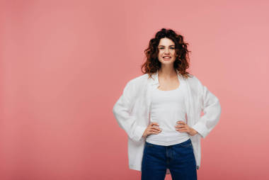 快樂的年輕女子站在臀部的手和粉紅色的微笑