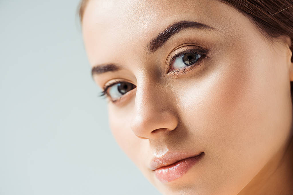 年轻漂亮的女人,嘴唇闪闪发光,金黄的眼影与灰色隔离 年轻漂亮的女人,嘴唇闪闪发光,金黄的眼影与灰色隔离