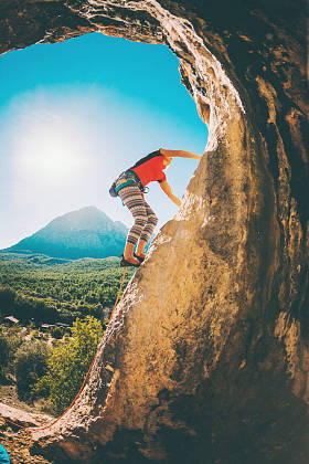 在美丽的山脉和蓝天的背景下的岩石登山者
