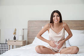 在卧室里腹痛的年轻妇女