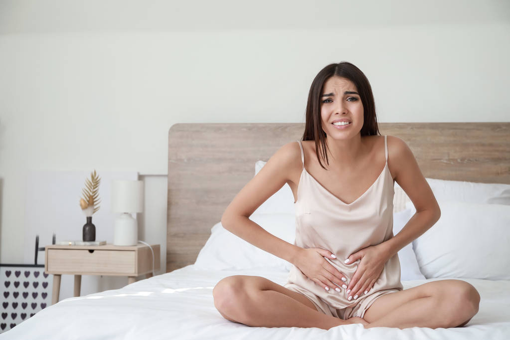 在卧室里腹痛的年轻妇女 在卧室里腹痛的年轻妇女