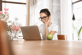 美丽的年轻学生女孩坐在室内使用笔记本电脑