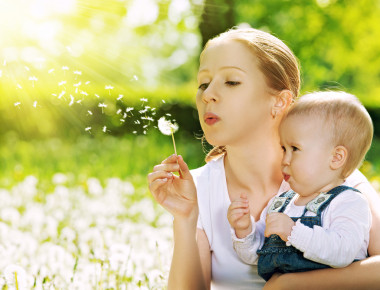 幸福的家庭。母亲和婴儿女孩吹上一朵蒲公英的花