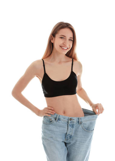 苗條的女人在白色背景的超大牛仔褲。完美的身體
