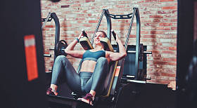 在健身房的训练机里蹲下跑的女运动员。腿部肌肉训练