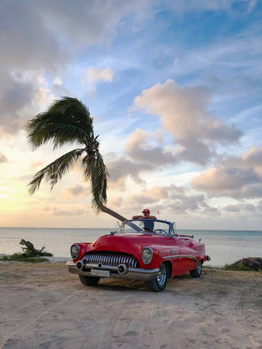 熱帶海灘上一位穿著紅色敞篷車的女人
