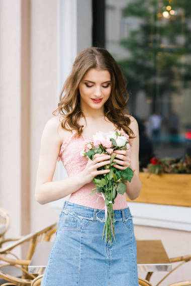 夏天在城市夏季咖啡館的露臺(tái)上，一個(gè)美麗的女孩手里拿著一束玫瑰花