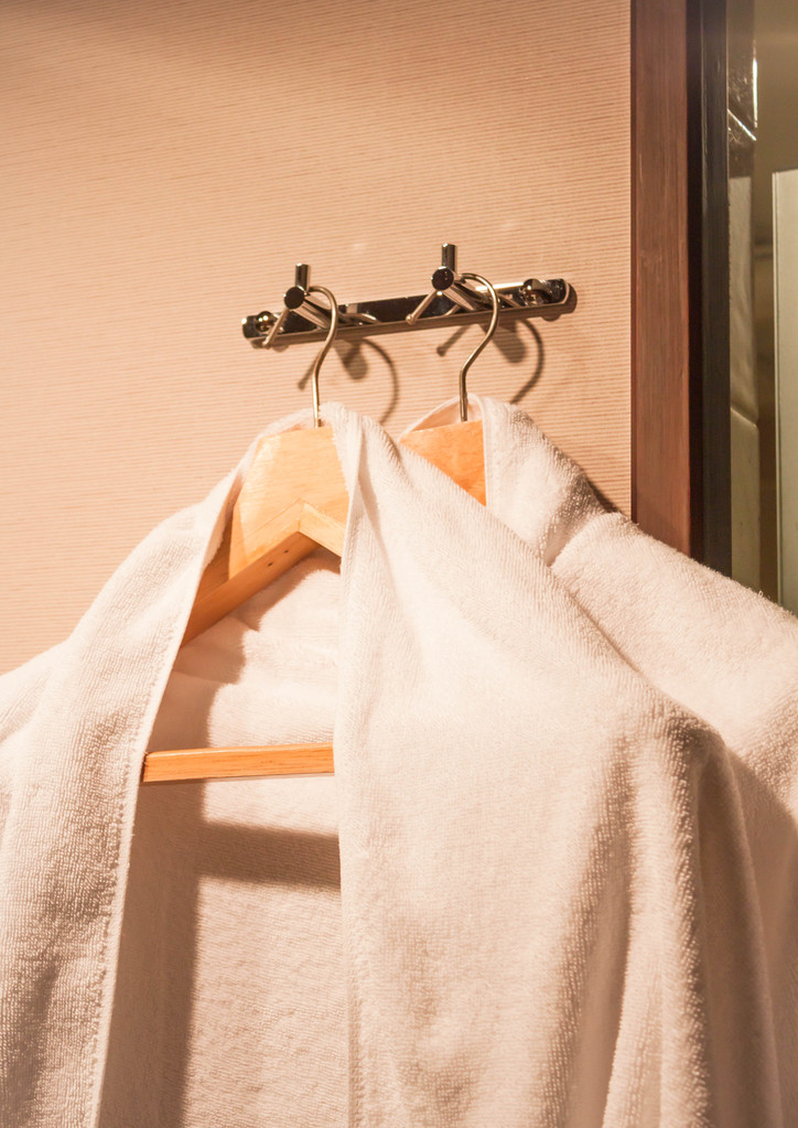 在酒店房间里的木衣架上的白毛巾 在酒店房间里的木衣架上的白毛巾