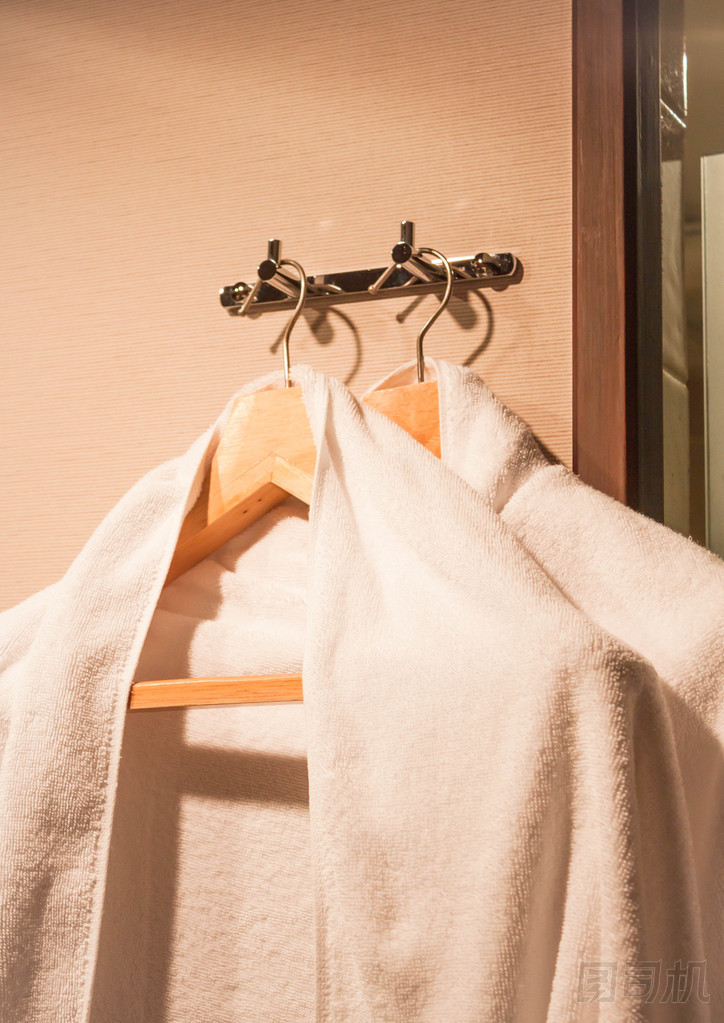 在酒店房間里的木衣架上的白毛巾