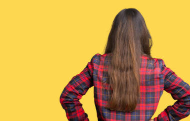 年輕美麗的黑發(fā)女人穿著夾克和眼鏡在孤立的背景站向后看著遠(yuǎn)離身體上的手