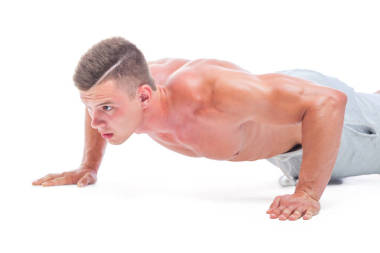 做俯卧撑的运动员在白色背景上被隔离。强壮的田径运动员 - 健身模型显示他完美的身体