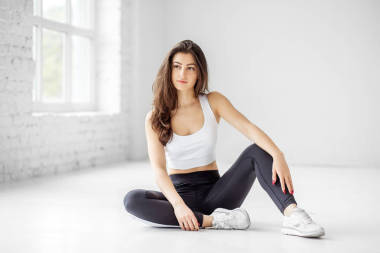 一個年輕女孩坐在健身房的地板上。運動理念,健康的生活方式,健身,伸展