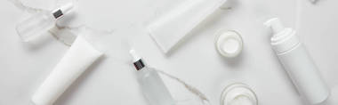 化妝品玻璃瓶全景拍攝，帶奶油的罐子，保濕管和在白色表面上的分配器