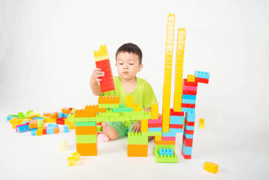 小男孩蹣跚學步玩塑料磚塊五顏六色與快樂