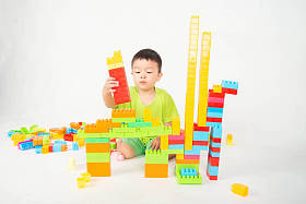 小男孩蹒跚学步玩塑料砖块五颜六色与快乐