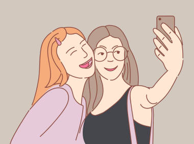 兩個(gè)快樂的年輕女孩采取自拍與智能手機(jī)