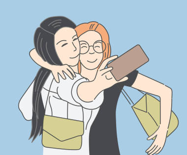 两个快乐的年轻女孩采取自拍与智能手机的蓝色背景