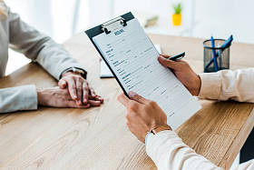 员工在招聘人员附近拿着剪贴板，带有简历信的裁剪视图