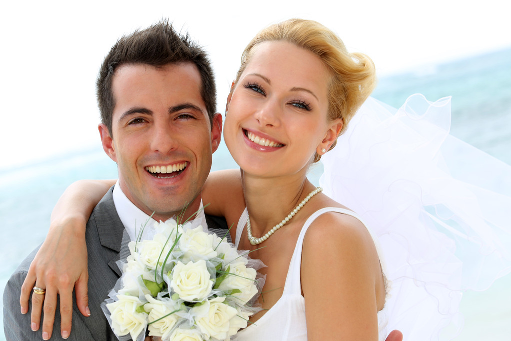 性格开朗的已婚的夫妇站在海滩上