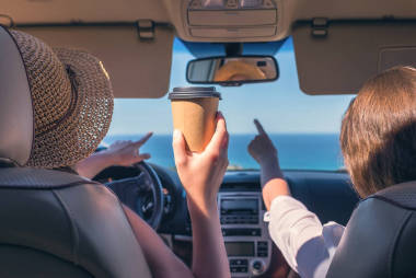 女司機(jī)戴著草帽，拿著紙杯咖啡開(kāi)車旅
