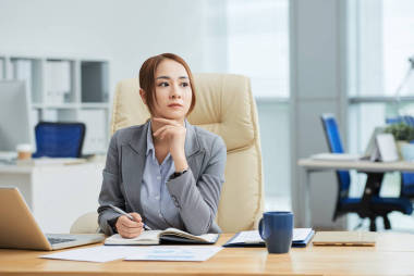 嚴(yán)肅的亞洲女商人坐在她的工作場(chǎng)所，用記事本思考新的商業(yè)理念在辦公室