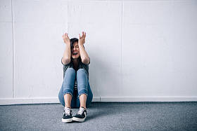 沮丧的黑发女人，双手坐在头上，在家里尖叫
