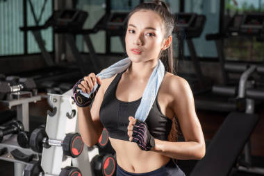 美丽的健身亚洲妇女与毛巾后健身房锻