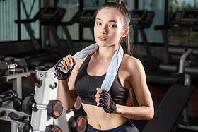 美丽的健身亚洲妇女与毛巾后健身房锻