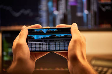 裁剪視圖的人拿著智能手機(jī)與圖形和圖表 