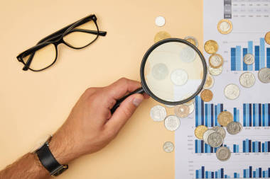 人拿着放大镜和看硬币的裁剪视图